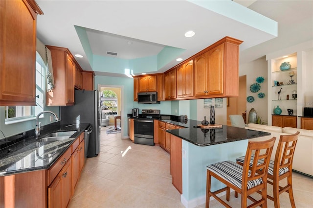 kitchen featuring a tray ceiling, visible vents, appliances with stainless steel finishes, a sink, and a peninsula