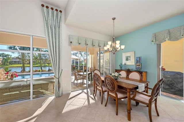 dining area featuring light tile patterned floors, a water view, and a notable chandelier