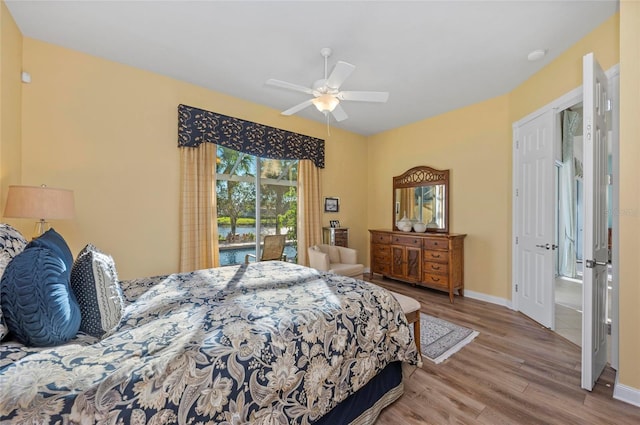 bedroom featuring access to outside, wood finished floors, a ceiling fan, and baseboards