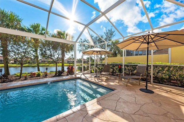 outdoor pool with glass enclosure, a patio area, and a water view