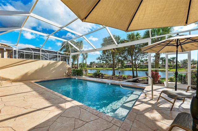 outdoor pool with glass enclosure, a patio area, and a water view