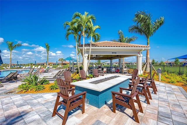 view of patio / terrace with a community pool, fence, a ceiling fan, and a gazebo