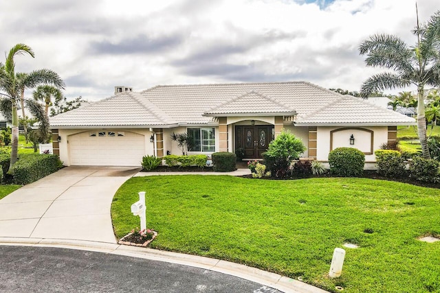 mediterranean / spanish house with a garage, a tiled roof, driveway, stucco siding, and a front lawn