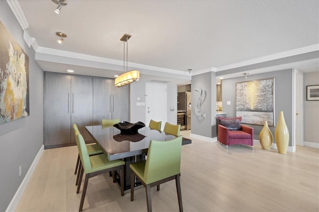 dining space with ornamental molding, baseboards, and light wood finished floors