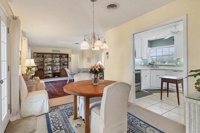 dining space featuring visible vents, light tile patterned floors, and ceiling fan with notable chandelier