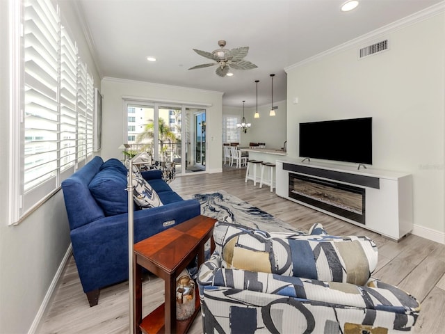 living area with ornamental molding, visible vents, light wood-style floors, and baseboards