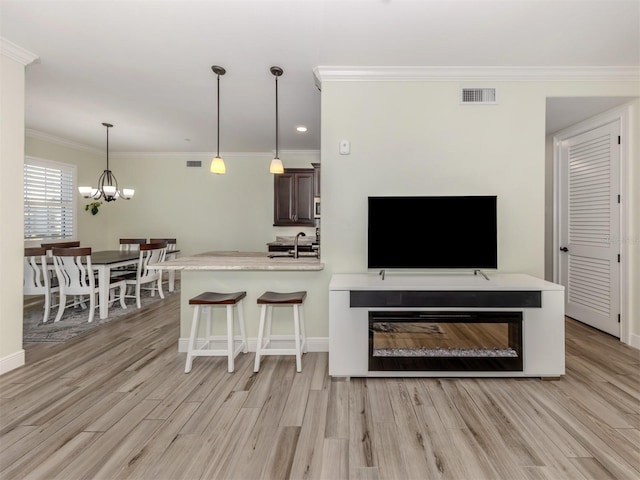 living room featuring light wood-style flooring, visible vents, a chandelier, and crown molding