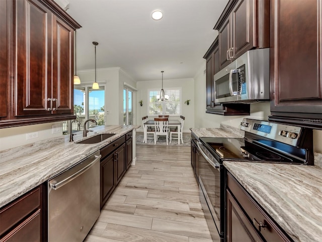 kitchen featuring a sink, light wood-style floors, ornamental molding, appliances with stainless steel finishes, and pendant lighting