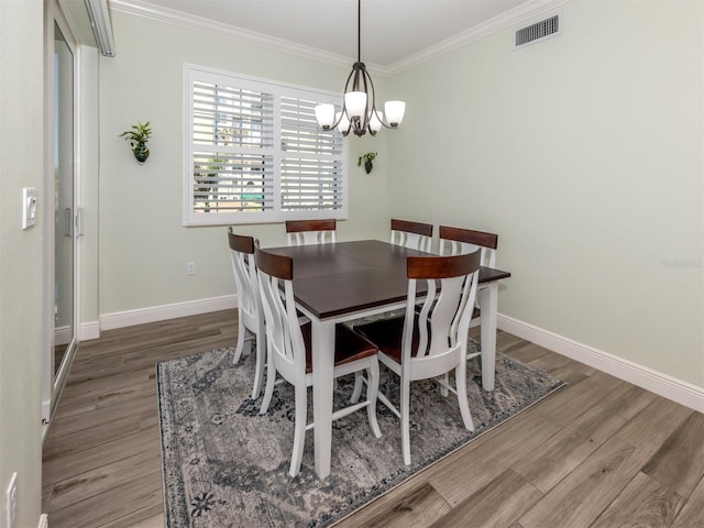 dining area featuring baseboards, visible vents, ornamental molding, wood finished floors, and a chandelier