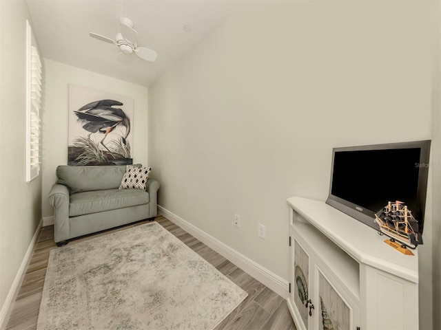 sitting room with a ceiling fan, lofted ceiling, baseboards, and wood finished floors