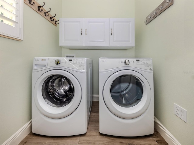 laundry room with baseboards, wood finished floors, cabinet space, and washer and dryer