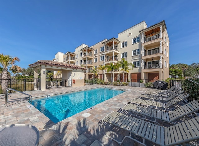 community pool with a patio, area for grilling, and fence