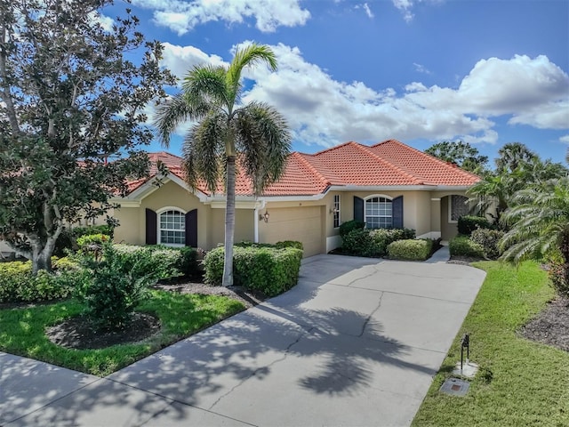 mediterranean / spanish-style home with driveway, an attached garage, a tile roof, and stucco siding