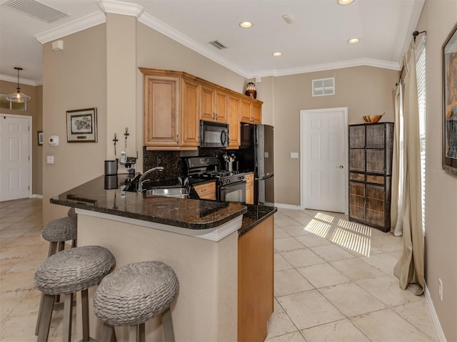 kitchen featuring black appliances, a kitchen bar, a sink, and visible vents