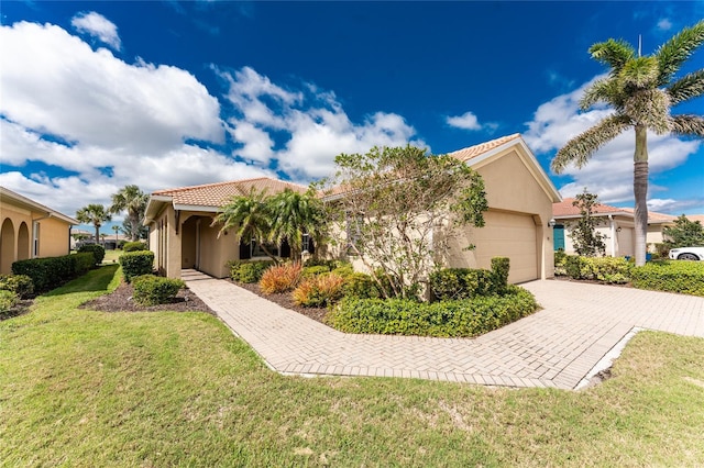 view of front of house with a garage, a tile roof, decorative driveway, stucco siding, and a front lawn