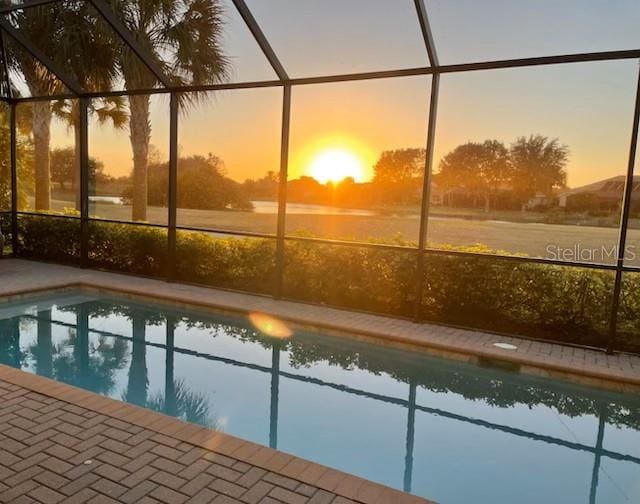 pool at dusk featuring a lanai, a patio area, and an outdoor pool