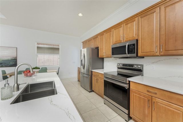 kitchen with crown molding, light tile patterned floors, appliances with stainless steel finishes, brown cabinetry, and a sink