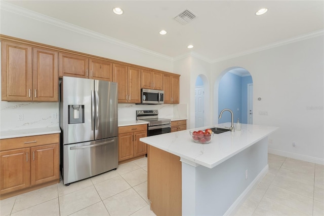 kitchen featuring brown cabinets, light tile patterned floors, appliances with stainless steel finishes, ornamental molding, and a sink