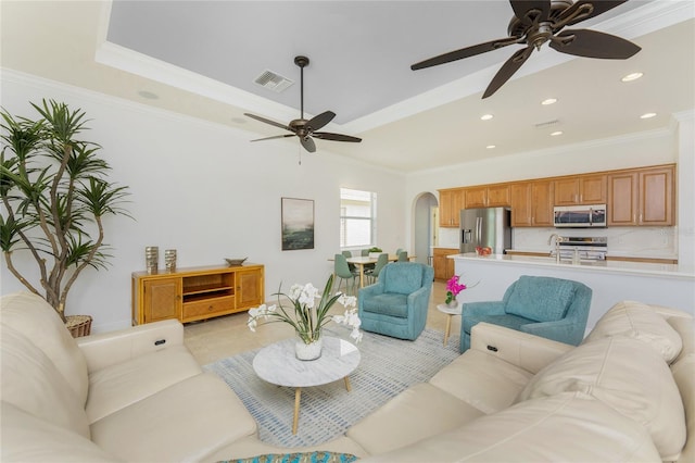 living room featuring arched walkways, light tile patterned flooring, visible vents, ornamental molding, and a tray ceiling