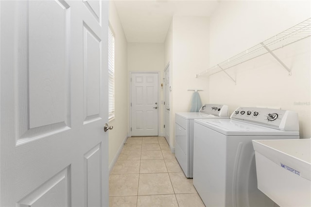 washroom with light tile patterned flooring, a sink, washer and dryer, laundry area, and baseboards