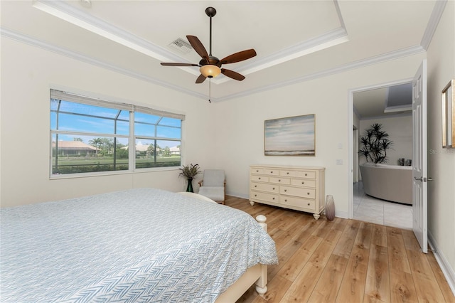 bedroom with visible vents, baseboards, ornamental molding, light wood-type flooring, and a raised ceiling