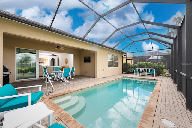 pool with a patio area, glass enclosure, a ceiling fan, and area for grilling