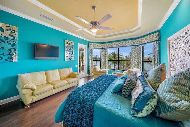 bedroom featuring a tray ceiling, crown molding, visible vents, ceiling fan, and wood finished floors