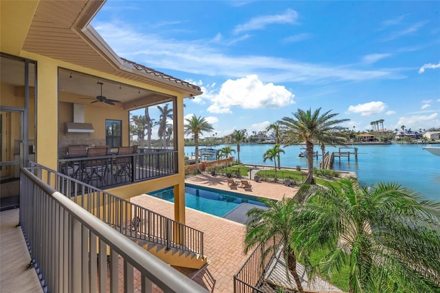 pool with a patio area, a ceiling fan, and a water view