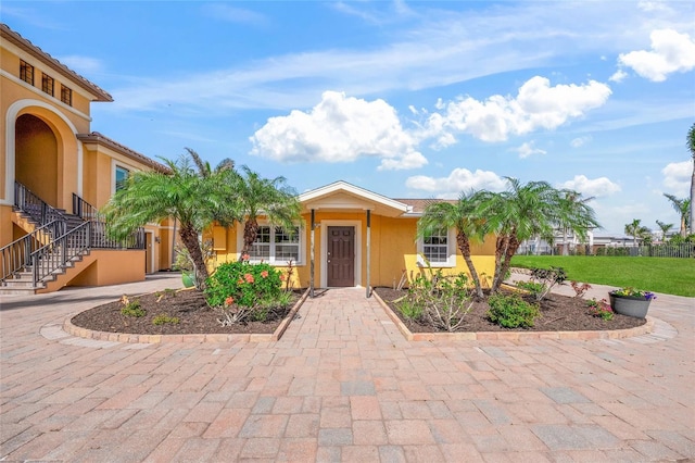 view of front of property featuring a tiled roof, stairway, and stucco siding