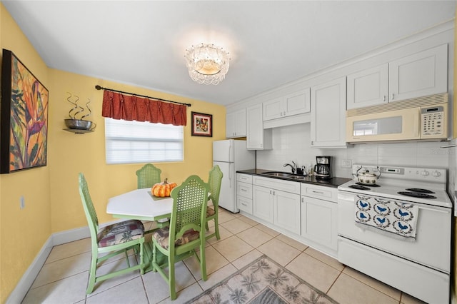 kitchen featuring light tile patterned floors, decorative backsplash, white cabinets, a sink, and white appliances