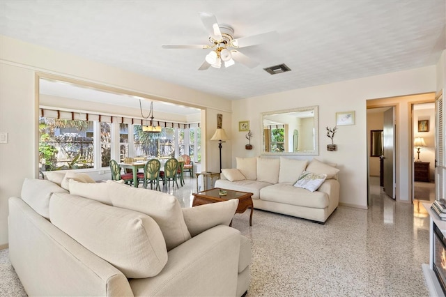 living area featuring speckled floor, visible vents, and ceiling fan