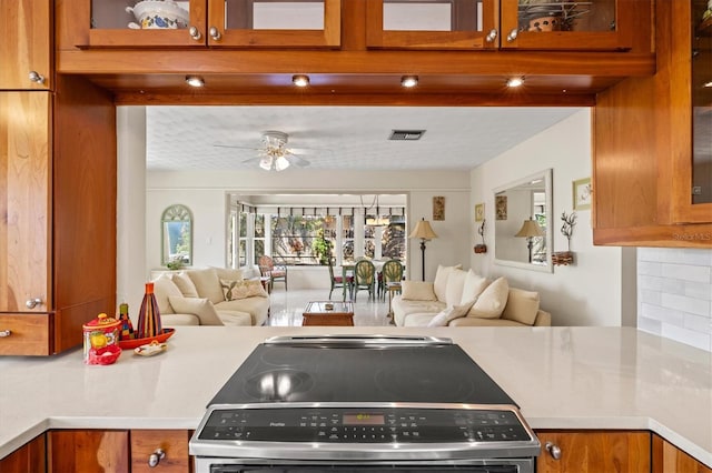 kitchen with visible vents, tasteful backsplash, open floor plan, brown cabinetry, and glass insert cabinets