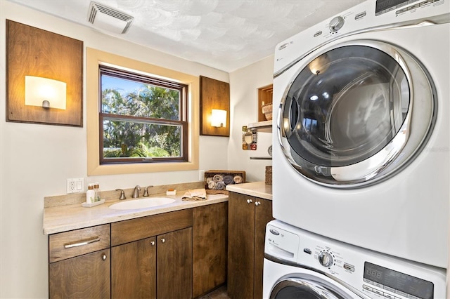 clothes washing area with a sink, laundry area, visible vents, and stacked washing maching and dryer