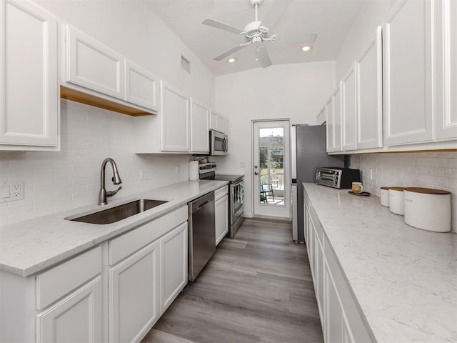 kitchen with stainless steel appliances, white cabinets, a sink, and light wood-style flooring