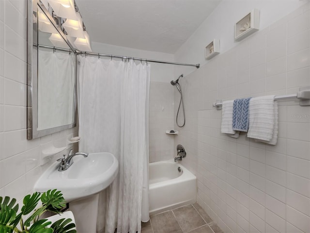 full bathroom featuring a sink, tile patterned flooring, shower / bathtub combination with curtain, and tile walls