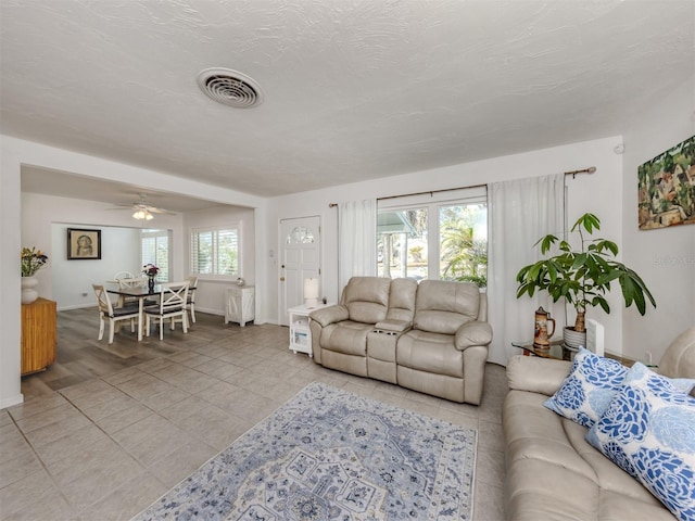 living area featuring a healthy amount of sunlight, light tile patterned floors, visible vents, and a textured ceiling