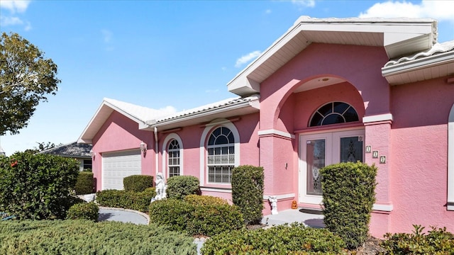 view of exterior entry with an attached garage and stucco siding