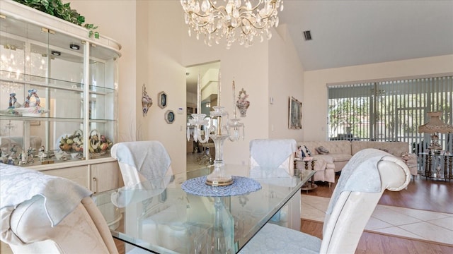 dining room with a notable chandelier, high vaulted ceiling, visible vents, and wood finished floors