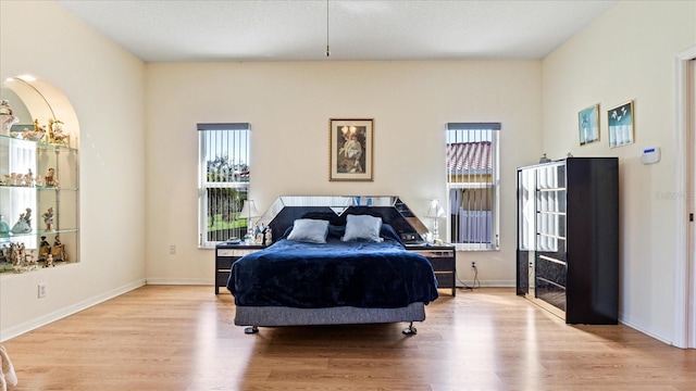 bedroom featuring multiple windows, wood finished floors, and baseboards