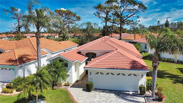 mediterranean / spanish home with a garage, a tile roof, decorative driveway, and stucco siding