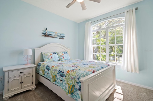 bedroom with multiple windows, baseboards, dark colored carpet, and a ceiling fan