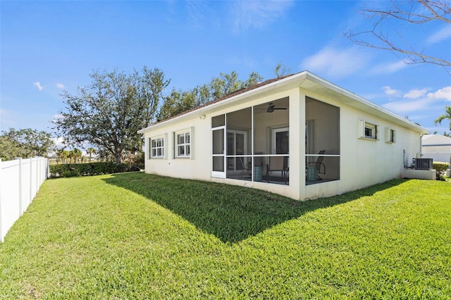 back of house featuring a sunroom, a fenced backyard, a lawn, and central air condition unit