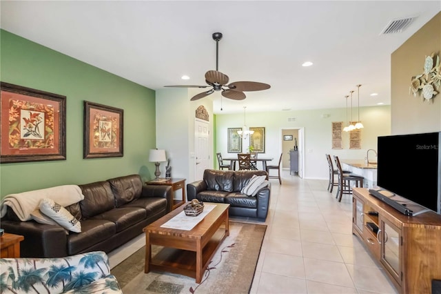 living area featuring ceiling fan with notable chandelier, recessed lighting, visible vents, and light tile patterned floors