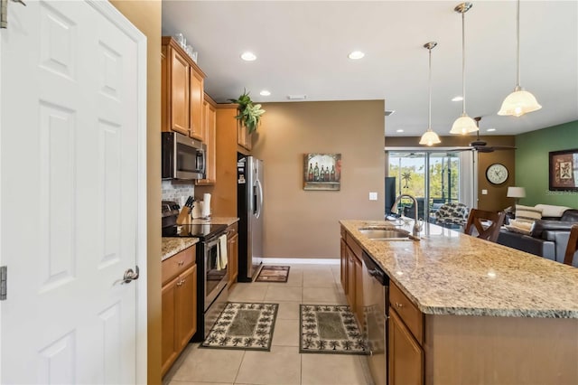 kitchen featuring brown cabinets, appliances with stainless steel finishes, backsplash, and a sink