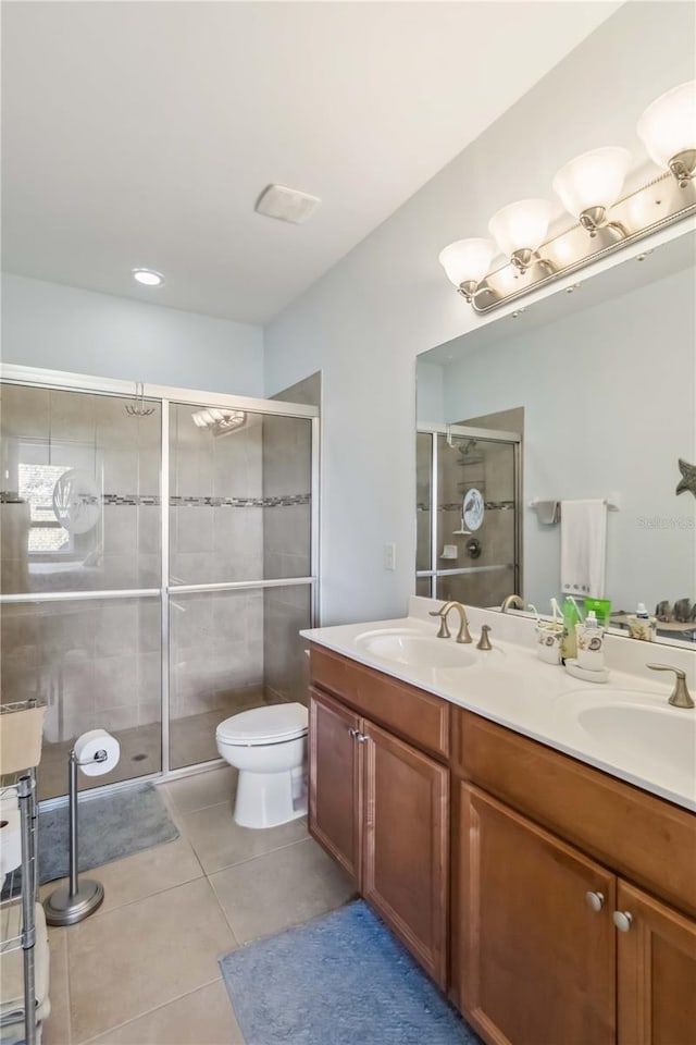 full bath featuring double vanity, a stall shower, tile patterned flooring, and a sink