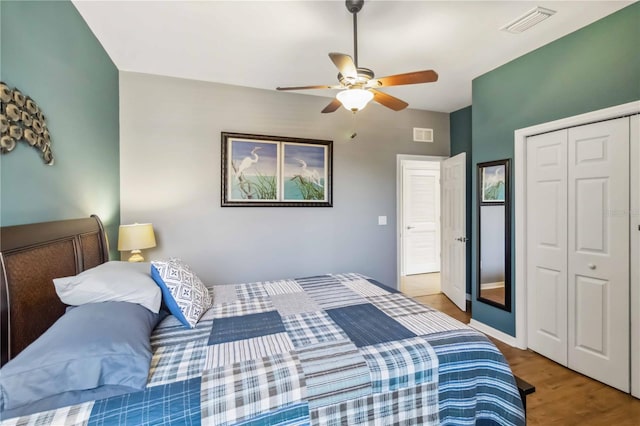 bedroom with a closet, visible vents, ceiling fan, and wood finished floors