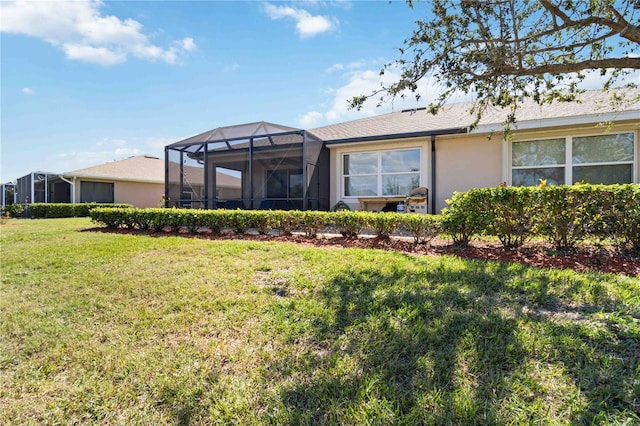 rear view of house featuring a yard, a lanai, and stucco siding