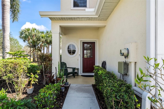 entrance to property featuring a porch and stucco siding