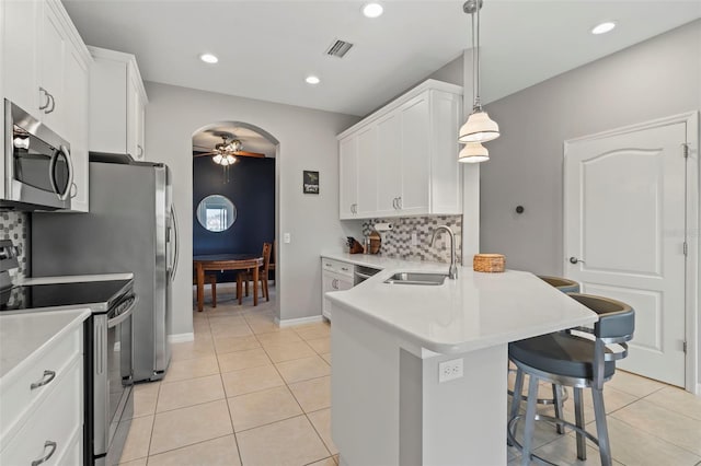 1050 Jonah Dr, North Port, FL 34289 - kitchen featuring arched walkways, stainless steel appliances, a sink, white cabinets, and backsplash