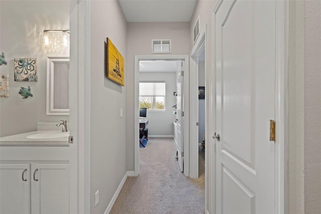 1050 Jonah Dr, North Port, FL 34289 - hallway with baseboards, visible vents, a sink, and light colored carpet
